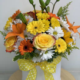 Yellow and orange mixed bouquet in a white hat box with a polka-dot ribbon