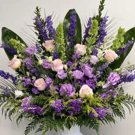 Lavender and pink floral arrangement in a white pedestal vase