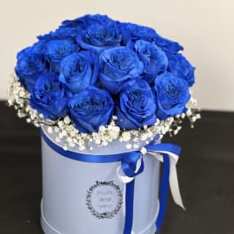 Blue rose bouquet in a round hat box with white baby's breath and ribbon