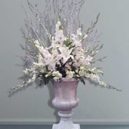 White floral arrangement in a pink pedestal urn