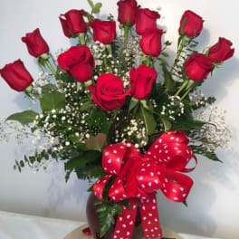 Bouquet of red roses in a vase with a heart-patterned ribbon