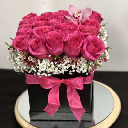 Hot pink roses arranged in a black box with a pink ribbon