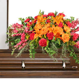 Bright orange and pink floral spray on a wooden casket