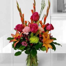 Bouquet of pink roses and orange lilies in a clear glass vase