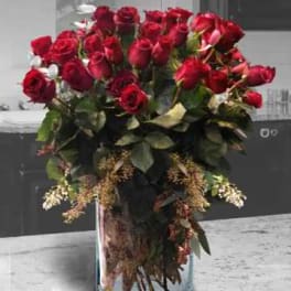 Tall bouquet of red roses in a clear glass vase