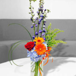 Mixed bouquet in a clear glass vase with red, orange, and blue flowers