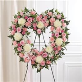Heart-shaped floral wreath of pink and white flowers on an easel