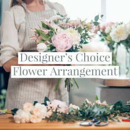 Florist in an apron holding a pastel pink and white mixed flower bouquet