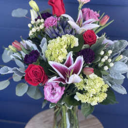 Mixed bouquet of roses, lilies, and hydrangeas in a glass vase