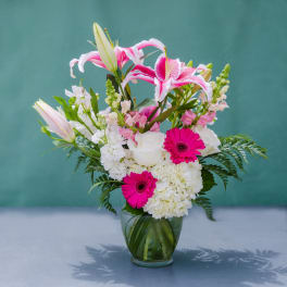 Pink lilies, white roses, and gerbera daisies in a glass vase