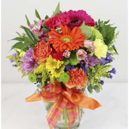 Colorful mixed flower bouquet in a glass vase with ribbon