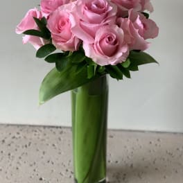 Pink roses arranged in a tall glass vase