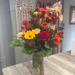 Mixed bouquet in a clear glass vase with a scarecrow decoration