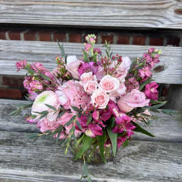 Pink and magenta mixed flower arrangement with roses and hydrangeas in a clear glass vase