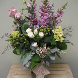Tall bouquet of pink and white flowers in a glass vase with lace ribbon