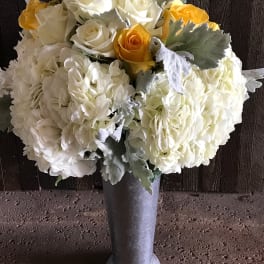 White and yellow rose bouquet in a tall silver vase