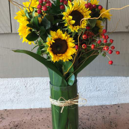 Sunflower bouquet in a glass vase with red berry accents
