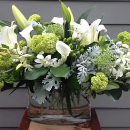 White lilies and green blooms in a clear glass vase