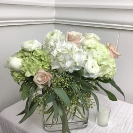 White and blush floral arrangement in a clear rectangular vase