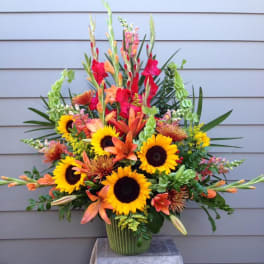 Bright mixed bouquet with sunflowers, orange lilies, and red gladiolus in a vase