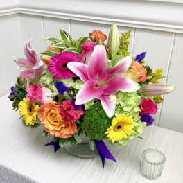 Mixed bouquet in a clear glass vase with pink lilies, roses, and gerbera daisies