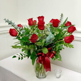 Bouquet of red roses in a clear glass vase with a red ribbon