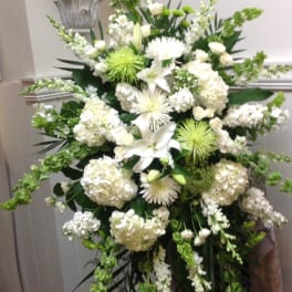 White funeral spray with lilies, hydrangeas, and green accents