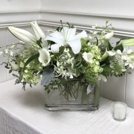 White lilies and green-white flowers in a clear glass vase