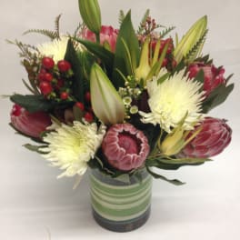 Bouquet of pink protea and white chrysanthemums in a striped glass vase