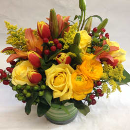 Bouquet of yellow roses, tulips, and lilies in a green striped vase