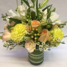 Mixed bouquet of white and peach flowers in a green glass vase