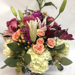 Bouquet of pink roses, lilies, and hydrangeas in a glass vase