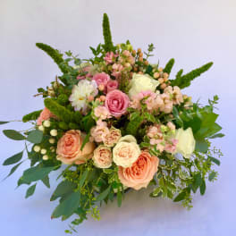 Bouquet of pink and cream roses with greenery and berry accents