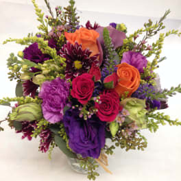 Mixed bouquet of purple, pink, and orange flowers in a glass vase
