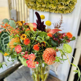 Mixed bouquet in a clear glass vase with pink, orange, and yellow blooms
