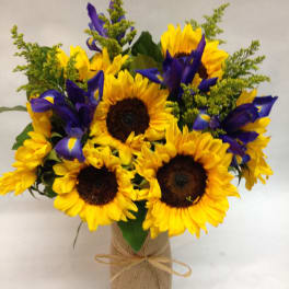 Bouquet of yellow sunflowers and purple irises in a burlap-wrapped vase