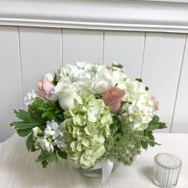White and pale pink bouquet with hydrangeas and roses in a low container