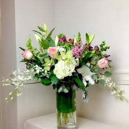 Mixed bouquet in a clear glass vase with pink, white, and green flowers