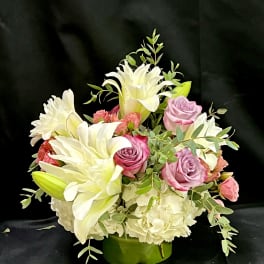 Pink roses and white lilies arranged in a green vase
