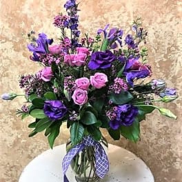 Pink and purple bouquet in a glass vase with a ribbon