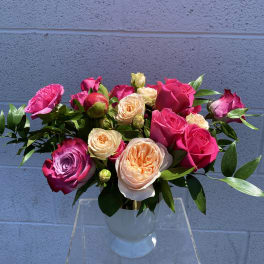 Bouquet of pink, peach, and lavender roses in a clear vase