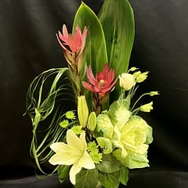 Tropical floral arrangement with pink and cream blooms in a vase