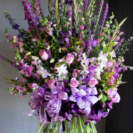 Tall bouquet of pink and purple flowers with ribbon bows