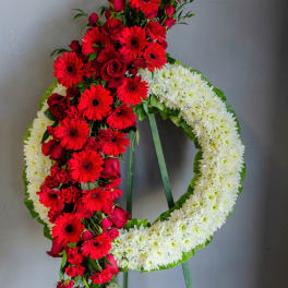 Standing floral wreath with red and white flowers on a green easel