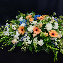 Low floral spray with peach gerberas, white blooms, and blue hydrangeas