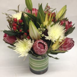Bouquet of pink protea and white chrysanthemums in a striped glass vase