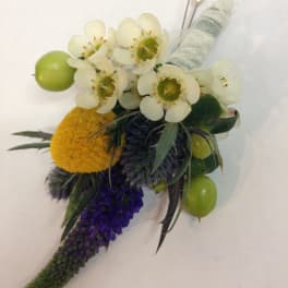 Boutonniere with white blossoms, green berries, and purple accents