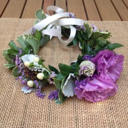 Floral wreath with purple blooms and white ribbon on burlap