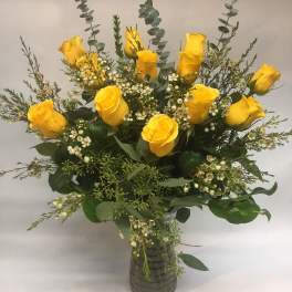 Yellow roses arranged in a clear glass vase with white filler flowers