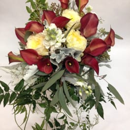 Bouquet of burgundy calla lilies and pale yellow roses with trailing greenery